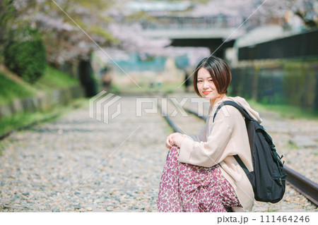 春の京都観光でインクラインの線路に座る女性 111464246