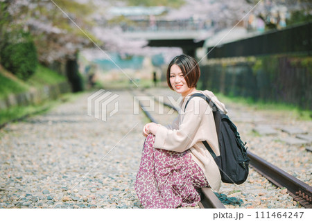 春の京都観光でインクラインの線路に座る女性 111464247
