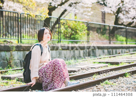 春の京都観光でインクラインの線路に座る女性 111464308