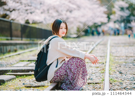 春の京都観光でインクラインの線路に座る女性 111464344