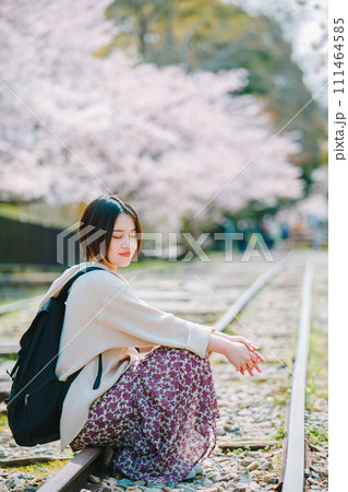 春の京都観光でインクラインの線路に座る女性 111464585