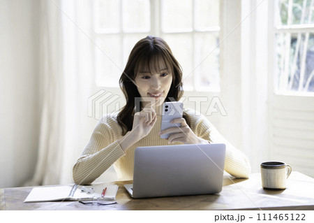 ノートパソコンを使いながらスマホを操作する女性 ノートパソコンを使いながらスマホを操作する女性 111465122