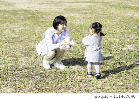 公園の芝生広場で遊ぶ園児と保育士 111467640