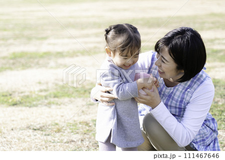 公園の芝生広場で遊ぶ園児と保育士 111467646