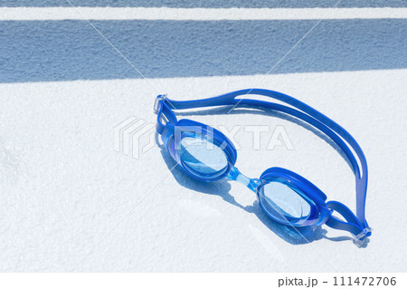 白い背景の上にある青い水泳用ゴーグルと濃い影 111472706