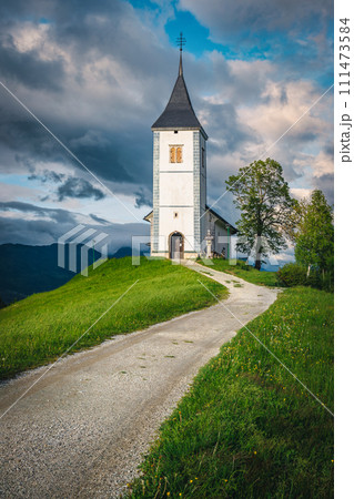Rural road and Saint Primoz church on the hill, Slovenia 111473584