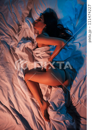 slender beautiful girl with a sexy body and ass in panties erotically lies on the bed under blanket in the bedroom. View from above top slender beautiful girl with a sexy body and ass in panties erotically lies on the bed under blanket in the bedroom. View from above top 111474227