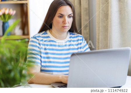 Focused Woman Working on Laptop in a Home Setting 111474922