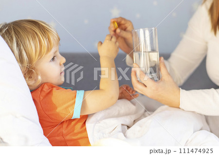 Toddler Receiving Medicine from Mother in Bed 111474925