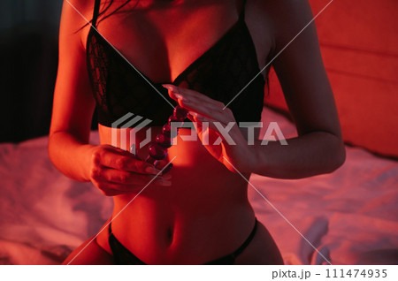 silicone butt anal plug in hands of a woman with a sexy body and breasts in bra sitting on bed in bedroom. Female sex toys for anal sex and orgasm silicone butt anal plug in hands of a woman with a sexy body and breasts in bra sitting on bed in bedroom. Female sex toys for anal sex and orgasm 111474935