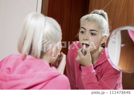 Beautiful young woman making make-up near mirror at home. Beautiful young woman making make-up near mirror at home. 111478646