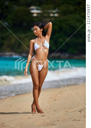 Beautiful asian girl in white bikini posing at the tropical beach Beautiful asian girl in white bikini posing at the tropical beach 111478937