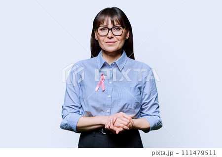 Middle-aged woman with pink ribbon symbolizing International Breast Cancer Day 111479511