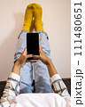 Woman with feet up using phone at home in a relaxing moment 111480651