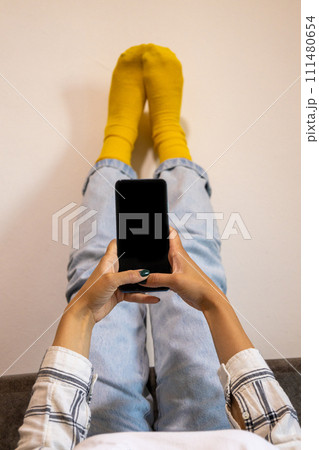 Feet up and using phone at home, relaxing moment. 111480654