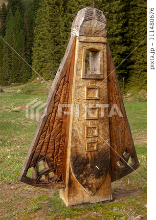 Wooden sculpture with a forest behind it. Grass and autumn mood.  111480676