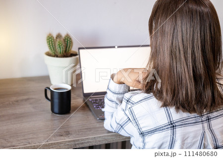 Casual brunette woman works on computer, back view. 111480680