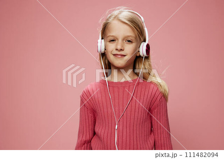 Happy Schoolgirl with Pink Headphones and Open Mouth Studio Portrait of a Stylish Caucasian Child A joyful and stylish schoolgirl wearing pink headphones, her beautiful smile and open mouth expressing 111482094