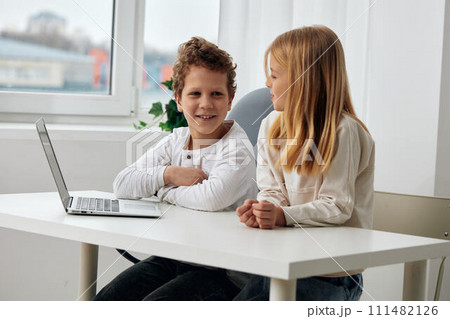 Happy siblings studying at home using laptops for online learning 111482126