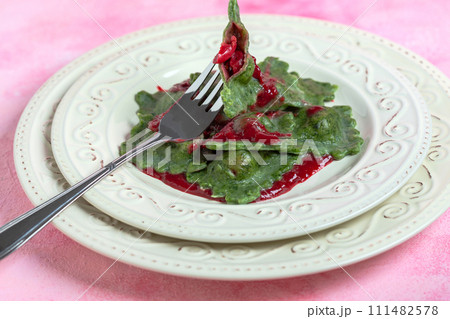 Green ravioli with cherry sauce. 111482578