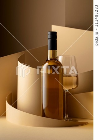 Bottle and glass of white wine on a beige background. Bottle and glass of white wine on a beige background. 111483283