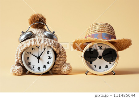 Spring forward fall back concept. Alarm clocks dressed in winter and summer accessories. Summer hat and glasses and winter hat as a symbol of season and time change. Switch to summer or winter time 111485044