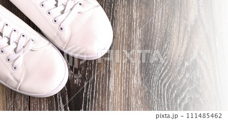 White sneakers on dark wooden surface. Shoes for women in sport fashion style 111485462