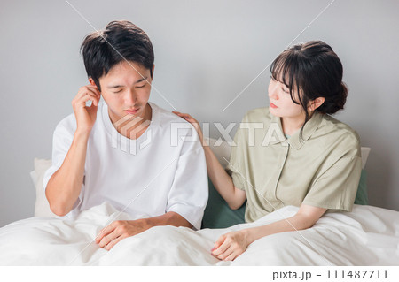 朝寝室で耳鳴り・難聴・外耳炎・中耳炎に悩む男性と心配する女性・夫婦・カップル 朝寝室で耳鳴り・難聴・外耳炎・中耳炎に悩む男性と心配する女性・夫婦・カップル 111487711