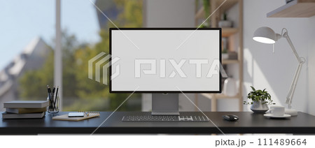 A modern home office features a computer mockup, a table lamp, and accessories on the table. 111489664