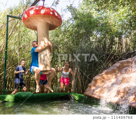 People trying to pass water obstacle course in adventure park 111489768
