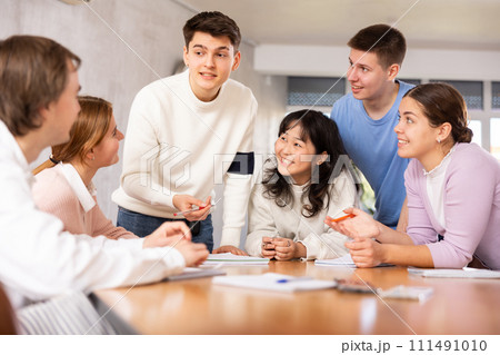 Interested young student taking part in group discussion Interested young student taking part in group discussion 111491010