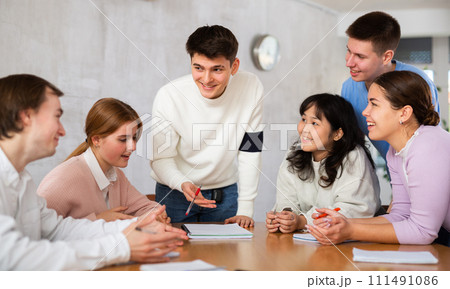 Young male tutor teaching group of students in college 111491086