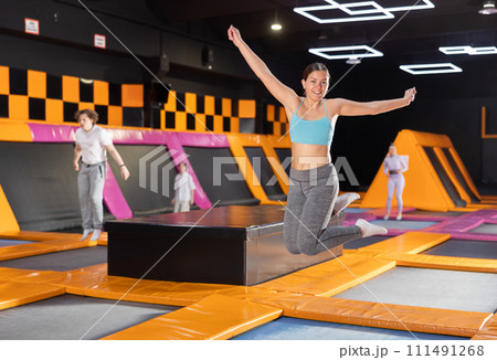 Young woman in sport clothes high jumping in trampoline arena Young woman in sport clothes high jumping in trampoline arena 111491268