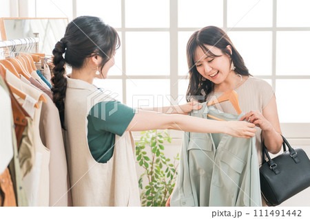 アパレルショップで洋服を買い物・ショッピングする女性とショップ店員 111491442
