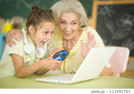 Portrait of grandmother and daughter playing computer game Portrait of grandmother and daughter playing computer game 111491765