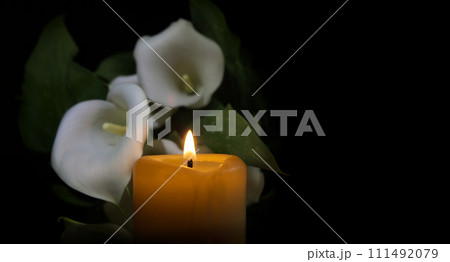 Candle flame and white calla lily in surrounding darkness Candle flame and white calla lily in surrounding darkness 111492079
