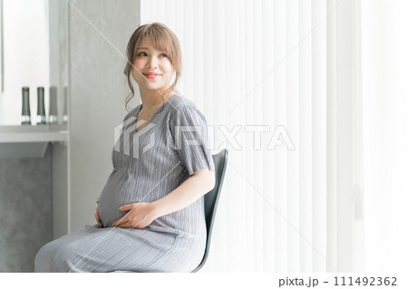 家のリビングで椅子に座る妊婦・マタニティフォト 111492362