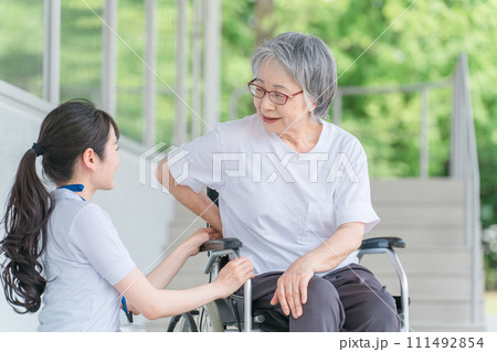 車椅子に乗る腰痛が治った笑顔の高齢者と介護士の女性 111492854