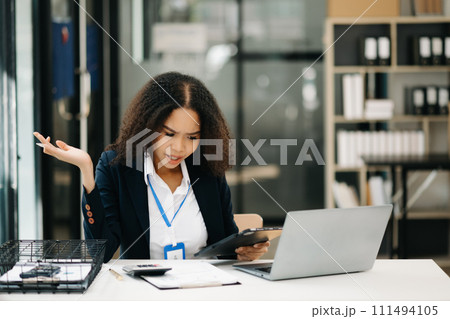 business woman is stressed, bored, and overthinking from working on a tablet. business woman is stressed, bored, and overthinking from working on a tablet. 111494105