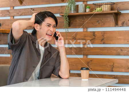 カフェで電話する若いアジア人男性（うっかりミス・ヒューマンエラー） 111494448