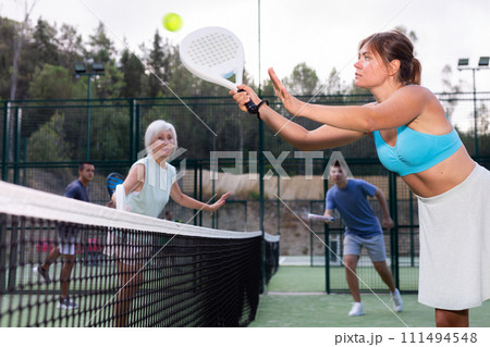 Sportive girl with racquet playing padel in court 111494548