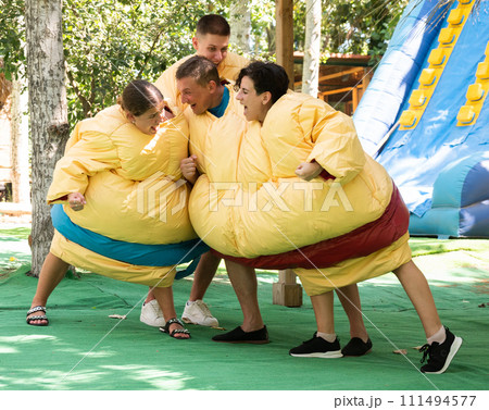 Cheerful friends having fun on fight arena in inflatable sumo twin suits 111494577