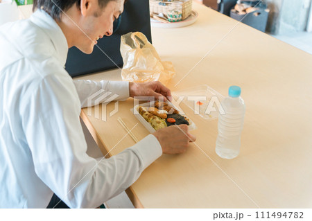 コンビニ・スーパーの弁当を食べるアジア人男性ビジネスマン(一人暮らし・独身・不健康・栄養バランス) コンビニ・スーパーの弁当を食べるアジア人男性ビジネスマン(一人暮らし・独身・不健康・栄養バランス) 111494782