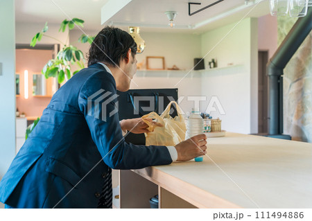 帰宅後コンビニ弁当を食べようとするスーツ姿のビジネスマン男性（不健康・単身赴任・孤独・離婚） 111494886
