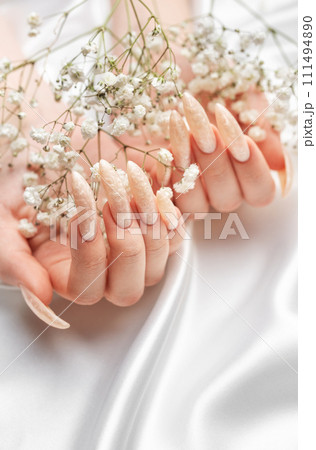 Female Hands on a white silk background with beautiful pearl manicure.Hands on a brown background and beautiful pearl manicure Female Hands on a white silk background with beautiful pearl manicure.Hands on a brown background and beautiful pearl manicure 111494890