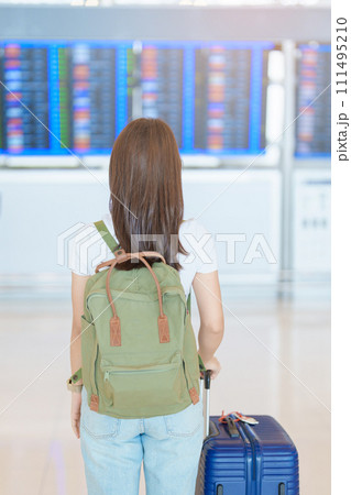 Young woman with bag and luggage looking to flight time information board in international airport, before check in. Travel, Vacation, trip and Transport concept 111495210