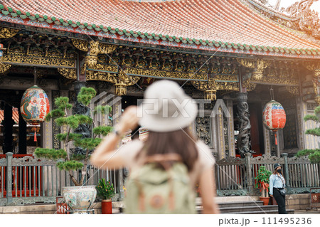 woman traveler visiting in Taiwan, Tourist with hat sightseeing in Longshan Temple, Chinese folk religious temple in Wanhua District, Taipei City. landmark and popular. Travel and Vacation concept 111495236