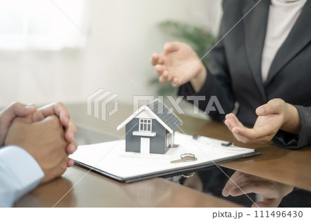 A real estate agent with a House model is talking to clients about buying home insurance. Home insurance concept 111496430