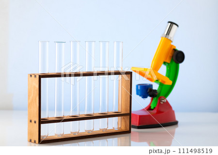 Empty chemical test tubes on a stand and a children's microscope. Chemistry lessons at school 111498519