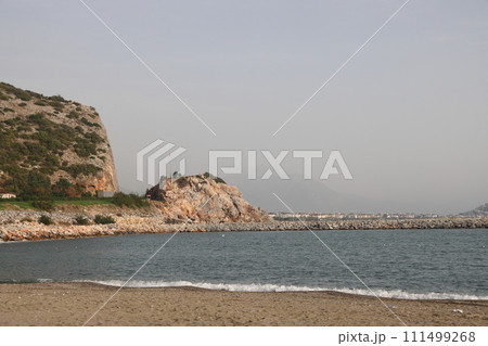 Storm at sea on Cleopatra Beach, foam waves against the background of the historic mountain, Alanya, November 2021. 111499268